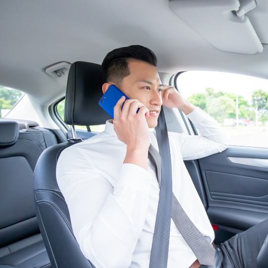 young man wearing office attire  sitting in his parked car listening to an Affordable Counselling Solutions therapist on his mobile phone 