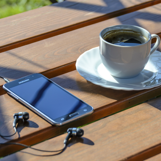 mobile phone with earplugs and cup of black coffee while waiting for a phone call from a Affordable Counselling Solutions therapist 