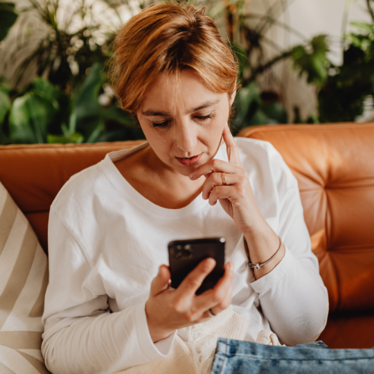 older woman contemplating making an online therapy booking with Affordable Counselling Solutions from her mobile phone