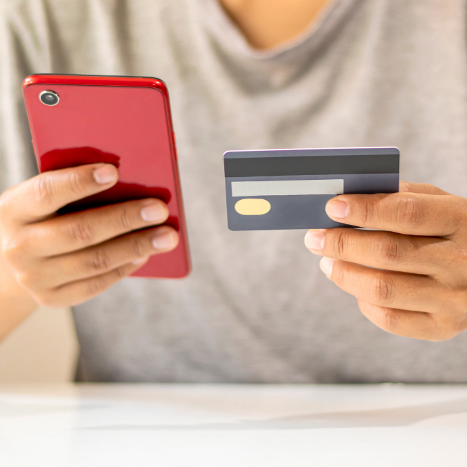 young person about to make an online therapy booking holding their credit card and mobile phone